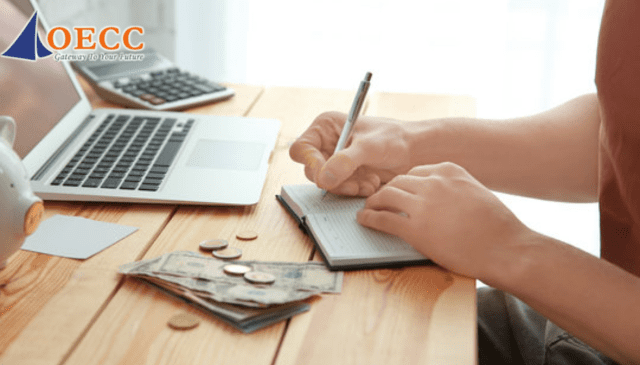 Du học sinh đang quản lý chi tiêu trên máy tính và sổ tay